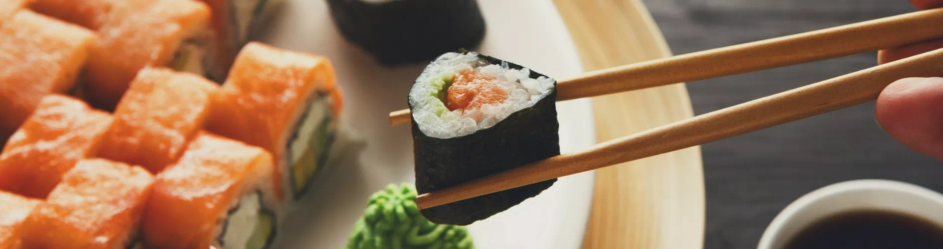 kawałek sushi trzymany pałeczkami